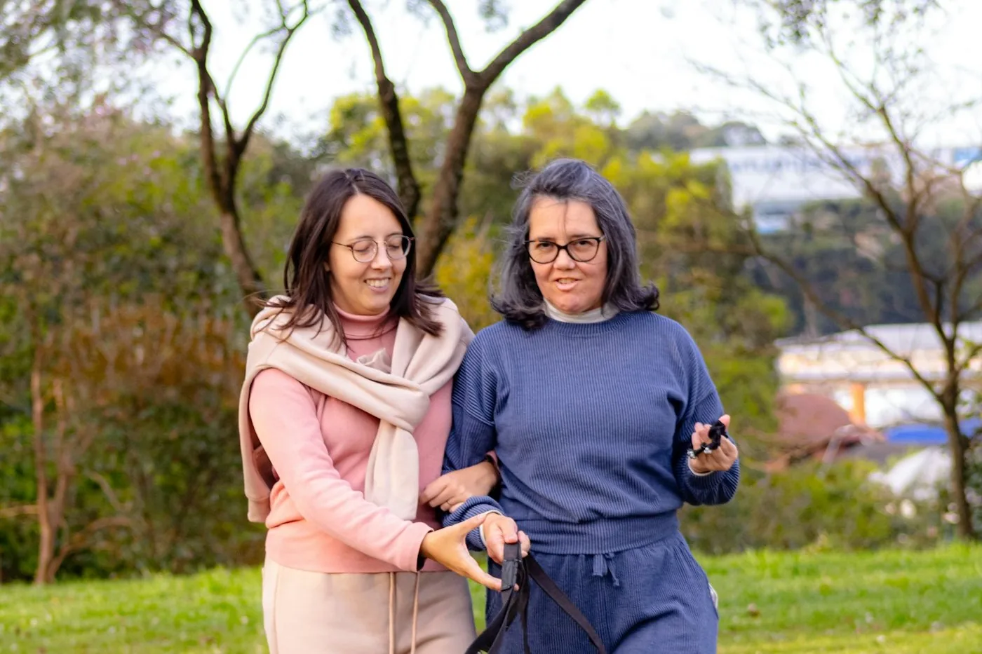 Two women walking together outdoors, one offering a supportive arm