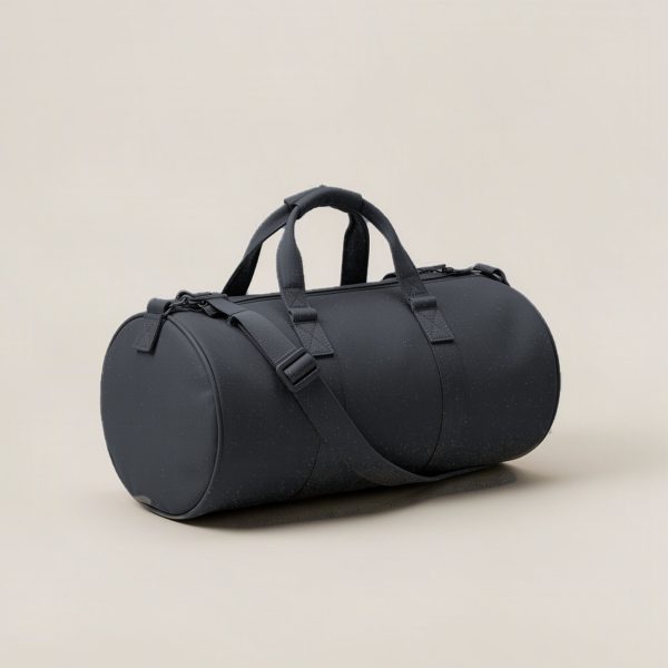 Cedar Duffel in Charcoal — cylindrical duffel bag with carry handles and a shoulder strap on a light grey backdrop