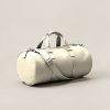 Cedar Duffel in Cream — cylindrical duffel bag with carry handles and a shoulder strap on a light grey backdrop