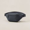 Cedar Hip Pack in Charcoal — compact hip pack with a zipped front pocket and a buckled waist strap on a light grey backdrop