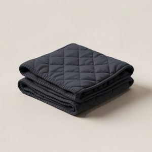Cedar Quilted Throw in Charcoal — quilted throw with diamond stitching, folded on a light grey backdrop