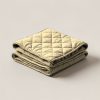 Cedar Quilted Throw in Sand — quilted throw with diamond stitching, folded on a light grey backdrop