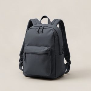 Driftwood Daypack in Charcoal — zip-top daypack with padded shoulder straps and a front pocket on a light grey backdrop