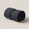 Ember Camp Throw in Charcoal — soft camp throw blanket, rolled with a strap on a light grey backdrop
