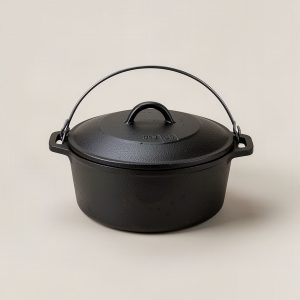 Ember Dutch Oven — black cast iron Dutch oven with a lid and wire bail handle on a light grey backdrop