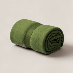 Granite Camp Throw in Moss — soft camp throw blanket, rolled with a strap on a light grey backdrop