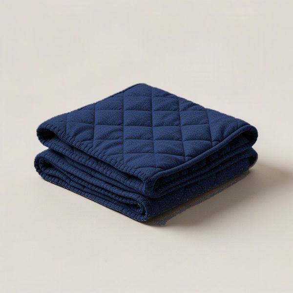 Granite Quilted Throw in Navy — quilted throw with diamond stitching, folded on a light grey backdrop