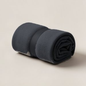Harbor Camp Throw in Charcoal — soft camp throw blanket, rolled with a strap on a light grey backdrop