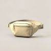 Juniper Hip Pack in Sand — compact hip pack with a zipped front pocket and a buckled waist strap on a light grey backdrop