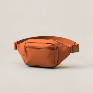 Lakeside Hip Pack in Rust — compact hip pack with a zipped front pocket and a buckled waist strap on a light grey backdrop