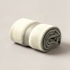 Juniper Camp Throw in Cream — soft camp throw blanket, rolled with a strap on a light grey backdrop