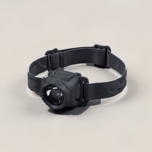 Ridgeline Headlamp in Charcoal — compact headlamp with a lens housing and an elastic headband on a light grey backdrop