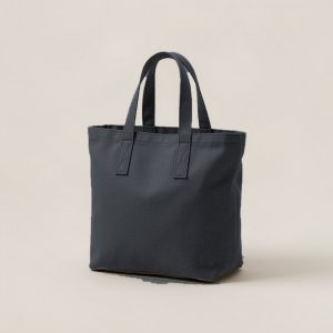 Ember Tote in Charcoal — canvas tote bag with two flat handles on a light grey backdrop