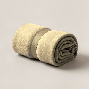 Trailhead Camp Throw in Sand — soft camp throw blanket, rolled with a strap on a light grey backdrop