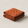 Trailhead Quilted Throw in Rust — quilted throw with diamond stitching, folded on a light grey backdrop