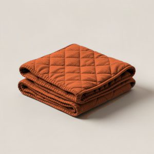 Trailhead Quilted Throw in Rust — quilted throw with diamond stitching, folded on a light grey backdrop