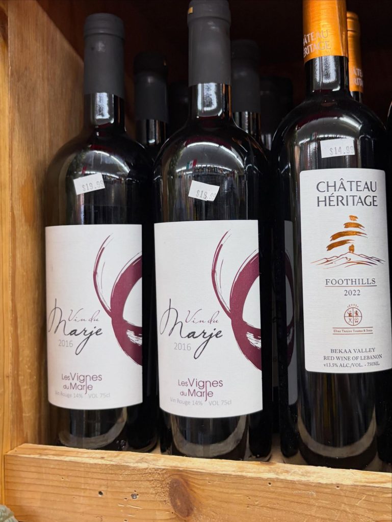 Red wines on a wooden shelf, including Château Heritage