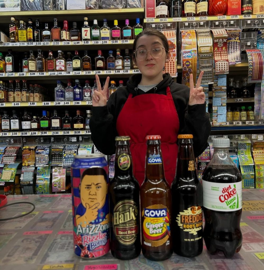 Team member at the counter with imported sodas and root beers
