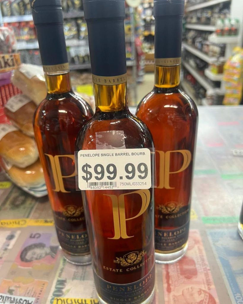 Penelope single barrel bourbon on the counter over foreign banknotes